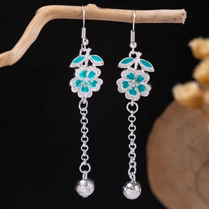 Macro detail of bohemian silver tassel earrings with turquoise petals on wood branch