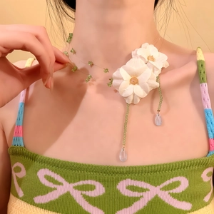 Dettaglio ravvicinato di un girocollo elegante con fiori in tessuto e perle di vetro viola