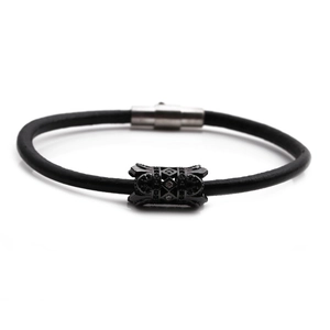 Detail of black leather bracelet with hollow carved metal bead and magnetic clasp closure