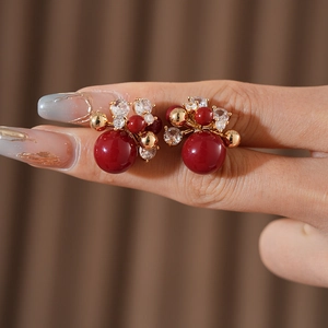 Macro shot of red cluster earrings with zircons and gold plated pearls on hand