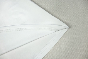 Nahaufnahme der präzisen Nähte und Saumdetails an einem weißen, schmal geschnittenen Kleid
