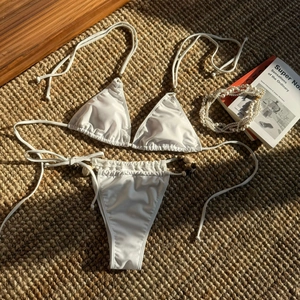 Close-up of white halter bikini with decorative amber beads on woven straw mat