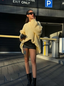 Outdoor street shot of a yellow cable knit oversized sweater with drop shoulders