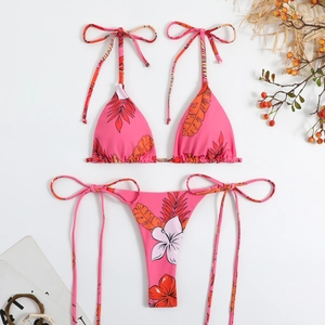 Flat lay of pink tropical floral bikini with halter top and tie-side bottoms detail