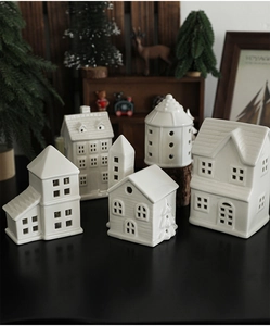 Set of white ceramic Christmas house ornaments displayed on a cozy wooden background
