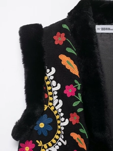 Detail der schwarzen Strickweste mit Blumenstickerei und Kunstpelzbesatz-Textur