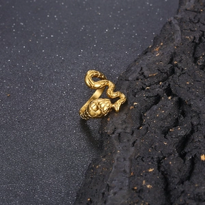 Macro shot of gold snake ring with detailed scale textures on dark rocky background