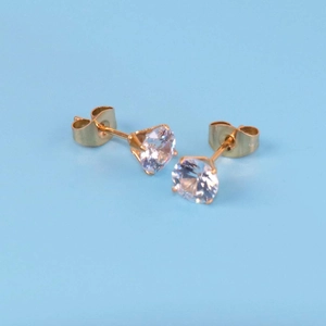 Detail of gold-plated stud earrings with round zircon stones and butterfly backs