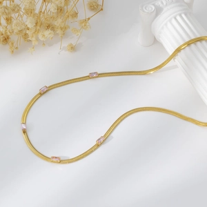 Close-up of a gold snake chain necklace with rectangular pink zircon stones