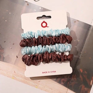 Detail of four-piece satin hair scrunchies in sky blue and brown on a display card