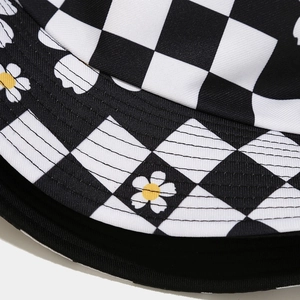 Detailed close-up of daisy prints and black and white checkerboard pattern on canvas bucket hat