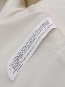 Detail view of the fabric label showing 100% cotton material composition in cream white