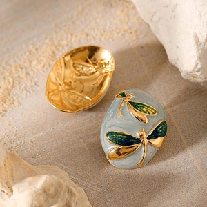 Detail of oval stainless steel gold earrings with enameled dragonfly and relief textures