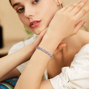 Detail of double-row tennis bracelet with white and purple zircon stones on a model wrist