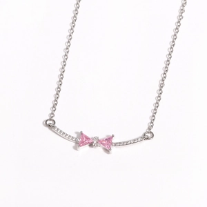 Macro view of pink zircon bow pendant with white micro-pave diamonds on silver chain