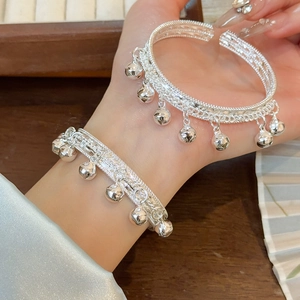 Détail du bracelet clochette argenté avec base tressée porté sur de la soie