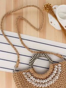 Minimalist straw woven handbag with natural shells and round handle for beach vacations