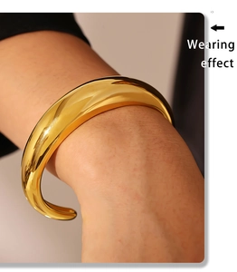 Macro shot of polished 18K gold plated thick crescent-shaped cuff bracelet on wrist