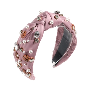 Pink knotted headband with basketball charms, pearls, and rhinestones on white background