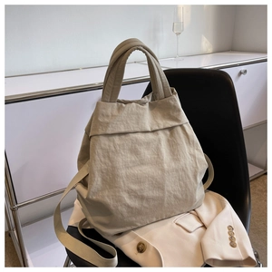 Detail of beige nylon tote bag on chair showing soft wrinkled texture and handles