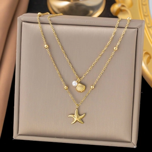 Zweilagige goldene Seestern- und Muschelkette mit Perlen auf einer edlen Schmuckschachtel