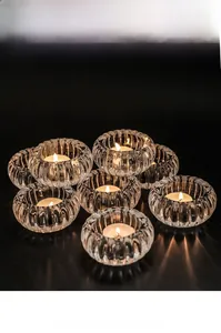 Détail d'un bougeoir en verre strié avec bougie chauffe-plat sur une surface miroir noire