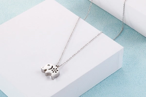 Macro shot of silver elephant pendant featuring hollow flower patterns and cross chain