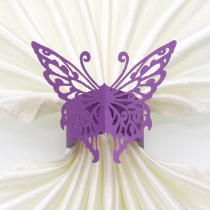Detailed laser-cut texture of purple butterfly paper napkin ring on satin fabric
