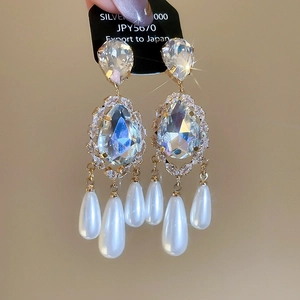 Macro shot of vintage gold-plated teardrop pearl earrings with brilliant zircon stones