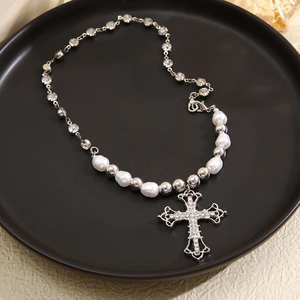 Vintage cross pendant necklace with pearls and sparkling rhinestones in a display