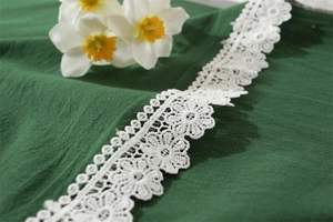 Close-up of white cotton lace border with intricate floral patterns on a table cloth