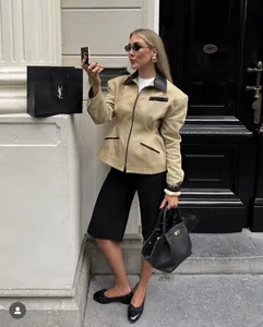 Detail of khaki jacket with black leather trim, shoulder pads and zip closure design