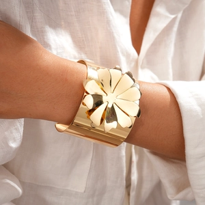 Gros plan d'un large bracelet manchette doré orné d'une grande fleur en métal 3D