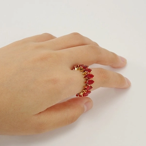 Adjustable gold ring with red marquise cut stones worn by a model on white background