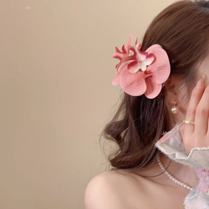 Detail of pink orchid flower hair clip with pearl accents worn by a female model