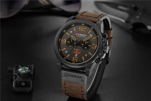 Detail of chronometer dial and brown leather strap on a tactical outdoor background