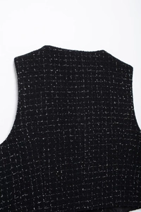 Gros plan sur le tissu en tweed noir aux fils argentés d'un ensemble gilet deux pièces