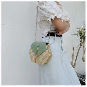 Detail of hexagonal straw crossbody bag featuring green leather flap and gold chain strap