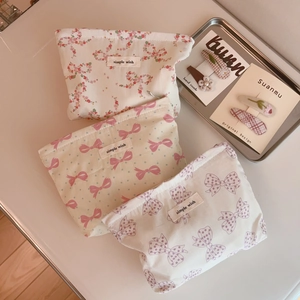 Detailed macro shot of three floral fabric makeup pouches with bow patterns and labels