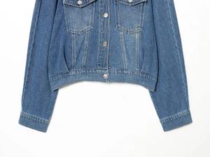 Detail of blue denim jacket showing washed texture, metal buttons, and stitching details
