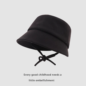 Détail d'un chapeau bob enfant en tricot noir avec nœud de jugulaire pratique