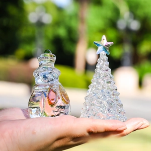 Close-up of faceted crystal snowman and Christmas tree figurine held in hand