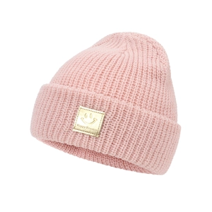 Close-up of pink knitted baby hat with thick rolled edge and golden happy face patch