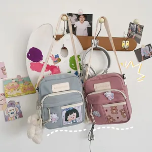 Détail d'un sac bandoulière en toile avec poche transparente et accessoire ours en peluche