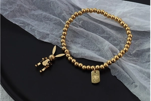 Detail eines 18k vergoldeten Perlenarmbands mit Glückshasen-Anhänger und Anhänger