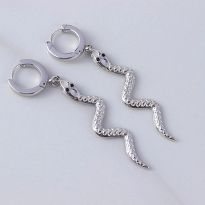 Detailed close-up of silver snake earrings with scale textures and black stone eyes