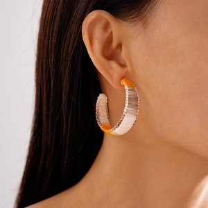 Close-up of hand-woven C-shaped earrings with colorful raffia cord in bohemian style