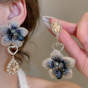 Dettaglio di eleganti orecchini a fiore con ricami e cristalli a forma di goccia
