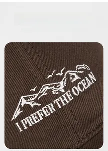 Gros plan de la broderie de montagne blanche et du texte sur la casquette en coton marron