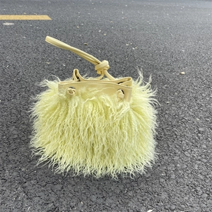 Detail of light yellow faux fur bucket bag featuring plush texture and PU leather drawstring